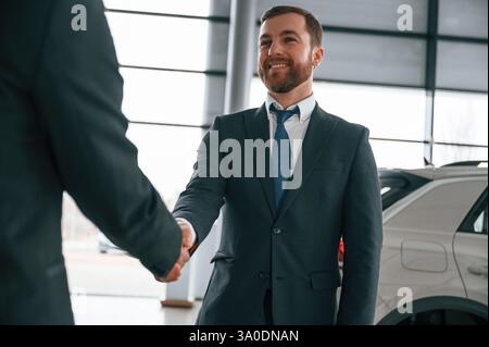 Due uomini d'affari sono in piedi nello showroom e fanno un accordo, stretta di mano. Foto Stock