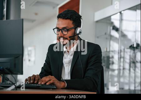 Un uomo indiano è seduto e lavora nello showroom. Foto Stock