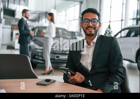Tre persone lavorano insieme nello showroom dell'auto. Foto Stock