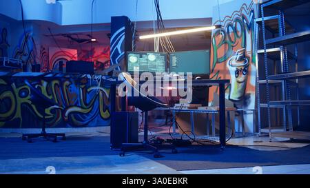 Sistema informatico high-tech che esegue codice dannoso in cantina vuoto, ripresa da fotocamera portatile. Il PC monitora in un nascondiglio criminale vuoto illuminato al neon utilizzato dagli hacker per commettere attività illegali, telecamera A. Foto Stock