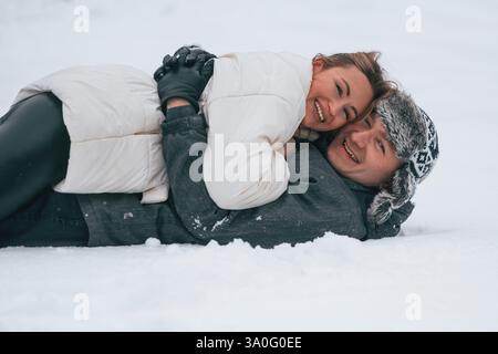 Una bella coppia è sdraiata sulla neve e si abbraccia a vicenda. Concezione dell'amore. Stagione invernale. Foto Stock