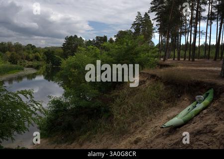 colorato paesaggio boschivo con alberi di pino su scogliera sabbiosa, kayak su pendio e nuvole magnifiche in estate Foto Stock
