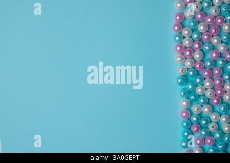 Più fili di perline di colori diversi sono posizionati in modo ordinato su uno sfondo blu brillante, evidenziando l'espressione artistica e il potenziale artigianale. Foto Stock