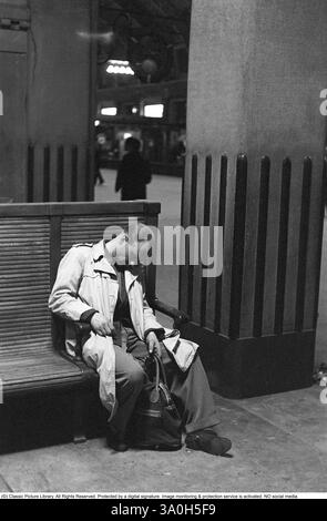Stazione centrale di Stoccolma nel 1954. La grande sala centrale è dove tutti passano da e per i treni. Un uomo si è addormentato seduto su una delle panchine, ancora con la mano intorno al manico della sua borsa. Kristoffersson rif. 1-12 Foto Stock