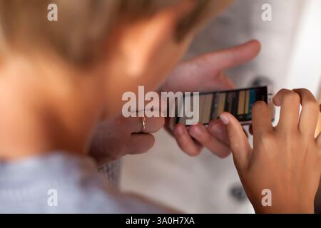 Questa fotografia ravvicinata mostra un bambino che interagisce con uno smartphone, scattato da una prospettiva a spalla. La mano del bambino e' visibile, ACT Foto Stock