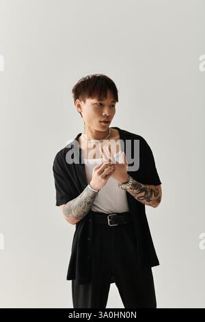 Un giovane e affascinante uomo asiatico si mette in posa, mettendo in risalto il suo stile unico e la sua fiducia. Foto Stock