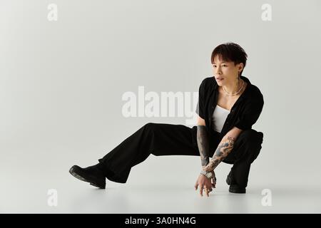 Un giovane e affascinante uomo asiatico colpisce una posa dinamica in uno studio pulito e minimalista. Foto Stock