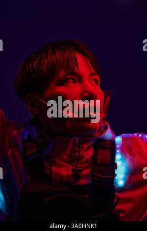 Un giovane e affascinante uomo asiatico è illuminato, sfoggiando il suo elegante outfit e la sua espressione affascinante. Foto Stock