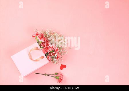 Garofani in una scatola rosa, sfondo floreale astratto di primavera. Bouquet moderno e creativo, concetto di vacanza minimalista. Cartolina per la giornata delle donne o della mamma, Foto Stock