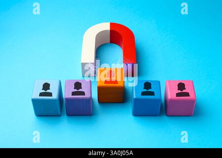 Magnete che attrae uno dei cubi colorati con figure umane su sfondo azzurro. Reclutamento o acquisizione di clienti Foto Stock