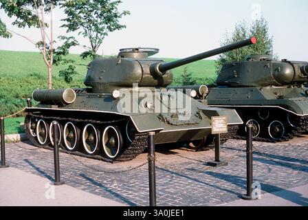 Vista frontale destra di un carro T-34/85 sovietico dotato di serbatoi di carburante esterni aggiuntivi e di un cannone da 85 mm esposto sul terreno del complesso commemorativo dello Stato ucraino 1985 Foto Stock