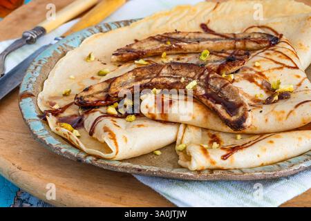 Crepe fatte in casa con banane caramellate e pistacchi schiacciati Foto Stock