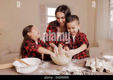 Mamma e bambini felici che cucinano insieme, divertimento per tutta la famiglia in cucina, mani disordinate, legame giocoso, cucina fatta in casa, momenti di gioia dell'infanzia. Foto Stock