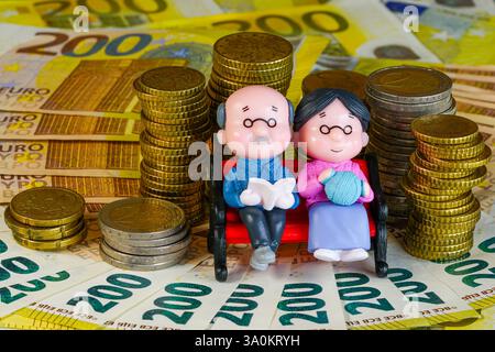 Simbolo di una pensione finanziariamente sicura, un paio di statuette di bambola seduto su una panchina Foto Stock