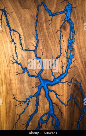 Una suggestiva lastra di legno presenta intricati motivi di resina blu, somiglianti a un fiume che scorre attraverso il grano. Questo pezzo artistico mette in risalto l'artigianato Foto Stock