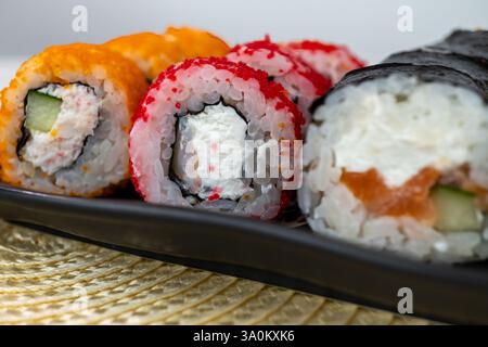 Primo piano di coloratissimi sushi roll su piatto nero Foto Stock