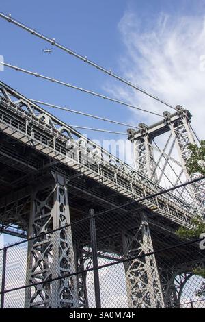 Guardando verso il ponte di Williamsburg sotto edifici storici e contemporanei, questa fotografia dall'angolo basso cattura il patrimonio architettonico della città. Foto Stock
