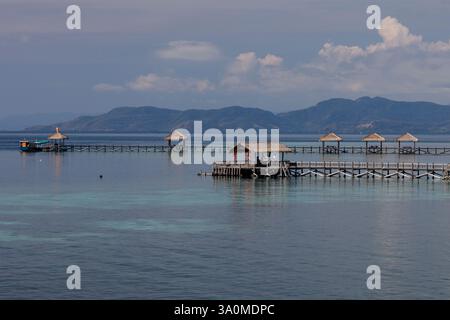 Vista dei moli e delle capanne tiki sull'isola di Seraja Kecil, conosciuta anche come Seraya, al largo della costa di Labuan Bajo, Indonesia. L'isola è la casa di Th Foto Stock
