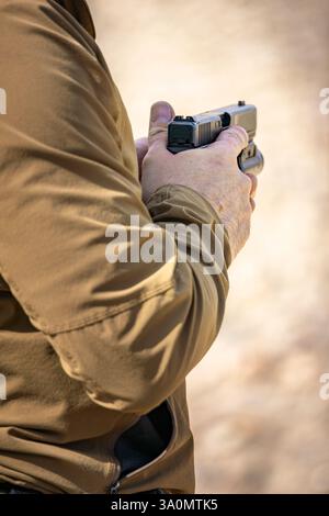 Primo piano di mani maschili con una pistola. Scatenare la disciplina delle dita, fuori dal grilletto, riposando fuori dalla guardia del grilletto a un tiro di pistola in California Foto Stock