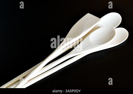 I nuovi cucchiai di legno si trovano su uno sfondo nero. Foto Stock