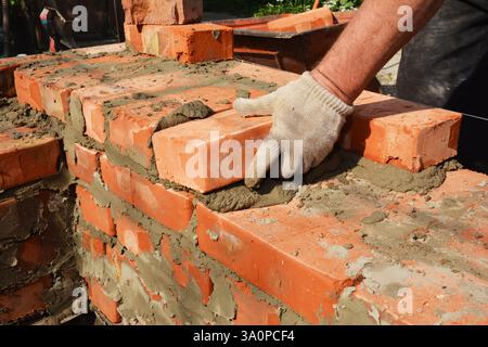 Muratore mani in guanti in muratura muratura muratura muratura parete casa. Muratura, muratura, muratura da vicino Foto Stock