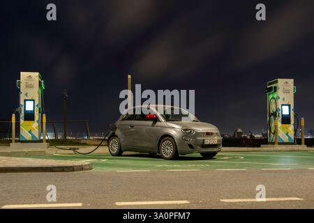 Un'auto elettrica Fiat 500 EV grigia del 2022 alla stazione EV. Veicolo elettrico che utilizza una fonte sostenibile, generatore eolico. Salvataggio, Foto Stock