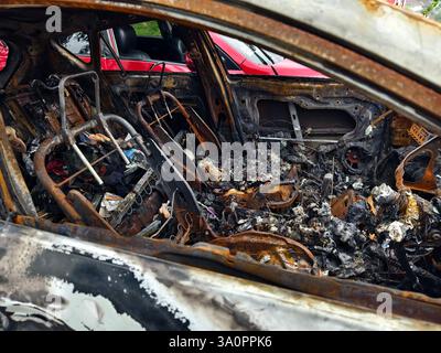 Resti carbonizzati di un veicolo lasciato indietro dopo un devastante incidente d'incendio. Foto Stock
