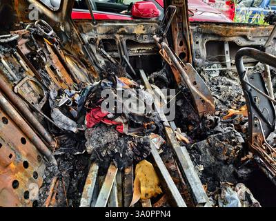 Resti carbonizzati di un veicolo lasciato indietro dopo un devastante incidente d'incendio. Foto Stock