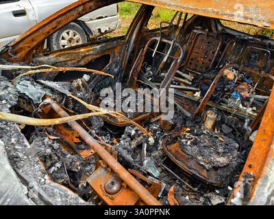Resti carbonizzati di un veicolo lasciato indietro dopo un devastante incidente d'incendio. Foto Stock