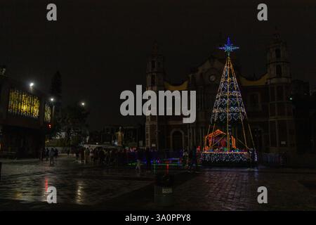 Un albero di Natale splendidamente decorato e un presepe illuminano la Basilica di Guadalupe di notte durante le festività. Foto Stock