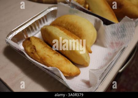 Vassoio pieno di panzerotti pronti, tradizionale piatto salato fritto pugliese. Ripieno di mozzarella e salsa di pomodoro Foto Stock