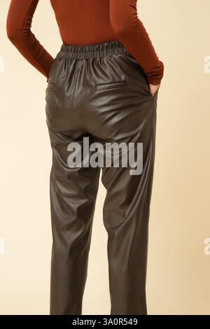 Fotografia in studio di una giovane modella donna che indossa pantaloni marrone in ecopelle con tacco alto Foto Stock