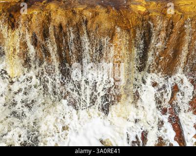 Dettaglio di una cascata nel Rio Tinto (fiume rosso) con la sua tonalità arancio-rosso a causa dei minerali di ferro ossidati. Vista aerea. Colpo di drone. Provincia di Huelva, AN Foto Stock