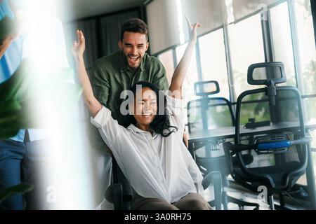 Dipendenti diversi eccitati che ridono godendo di attività divertenti durante la pausa di lavoro, lavoratori creativi e amichevoli Foto Stock