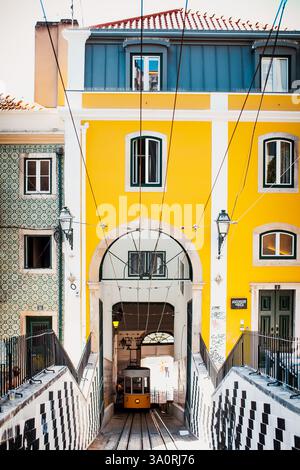 Una funicolare gialla sotto l'edificio di Lisbona. Il famoso Ascensor da Bica a Lisbona, in Portogallo. La funicolare gialla sale tra i colorati buildi Foto Stock
