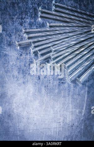 Collezione di chiodi da costruzione in acciaio inox su superfici metalliche graffiate Foto Stock