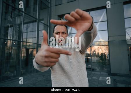 Fare un gesto fotografico. Bell'uomo nero e' all'aperto vicino all'edificio degli affari. Foto Stock
