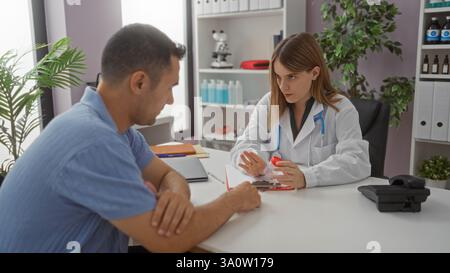 Donna medico che spiega il farmaco al paziente di sesso maschile in stanza clinica medica con piante e stetoscopio sulla scrivania. Foto Stock