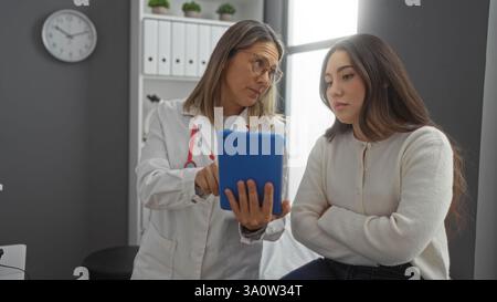 Medici e pazienti donne che discutono di assistenza sanitaria in un ufficio di clinica con un tablet, sottolineando un'interazione medica professionale in una moderna cli indoor Foto Stock