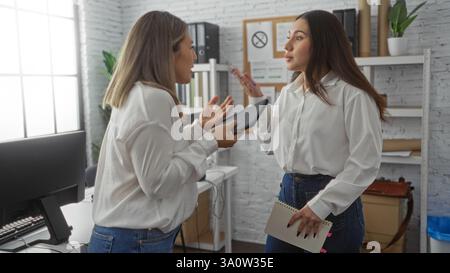 Due donne che discutono al chiuso in un ufficio con un notebook e un tablet, presentando un ambiente di lavoro professionale incentrato sulla collaborazione e. Foto Stock