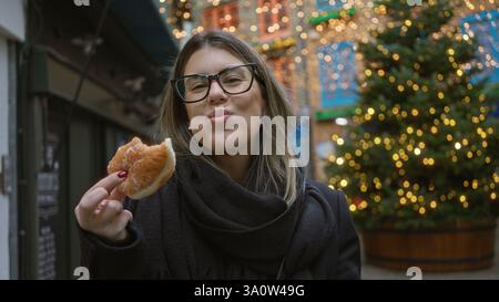 Donna che si diverte con le ciambelle natalizie nel cortile di neal a londra con le luci natalizie che illuminano splendidamente l'affascinante strada delle vacanze nel regno unito Foto Stock