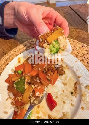 maschio che mangia in padella con verdure e riso, tenendo in mano una porzione piccola. Foto di alta qualità Foto Stock