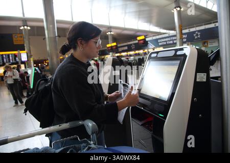 Donna che utilizza il check-in self-service all'aeroporto di Londra Heathrow, Inghilterra Foto Stock