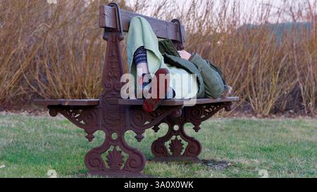 Donna che dorme su una panchina decorata. Foto Stock