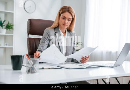 Fare i documenti. La donna in abiti da lavoro sta lavorando in ufficio. Foto Stock