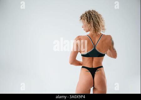 Vista posteriore. Giovane donna caucasica con forma fisica atletica è al chiuso di giorno. Foto Stock