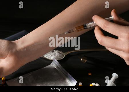 Tossicodipendenza. Donna con siringa su sfondo scuro, primo piano Foto Stock