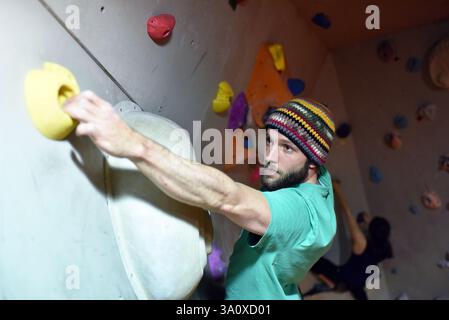 Giovane uomo sportivo bouldering in una sala di arrampicata - Sport al coperto Foto Stock