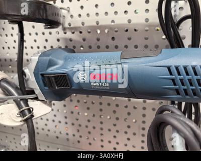 Bobruisk, Bielorussia - 22 febbraio 2025: La smerigliatrice di alta qualità è fissata a un clothespin in metallo, che ne mostra il design elegante e lo stile industriale. Foto Stock