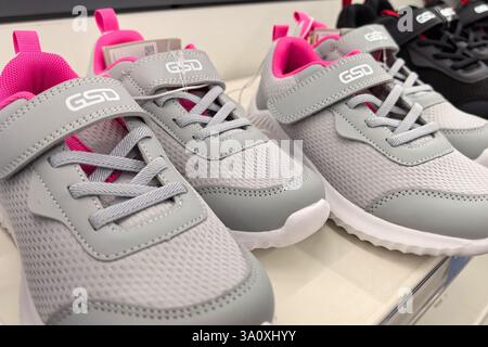 Bobruisk, Bielorussia - 22 febbraio 2025: Le eleganti scarpe da atletica sono esposte sugli scaffali dei negozi, con una miscela di tonalità grigio e rosa. Foto Stock